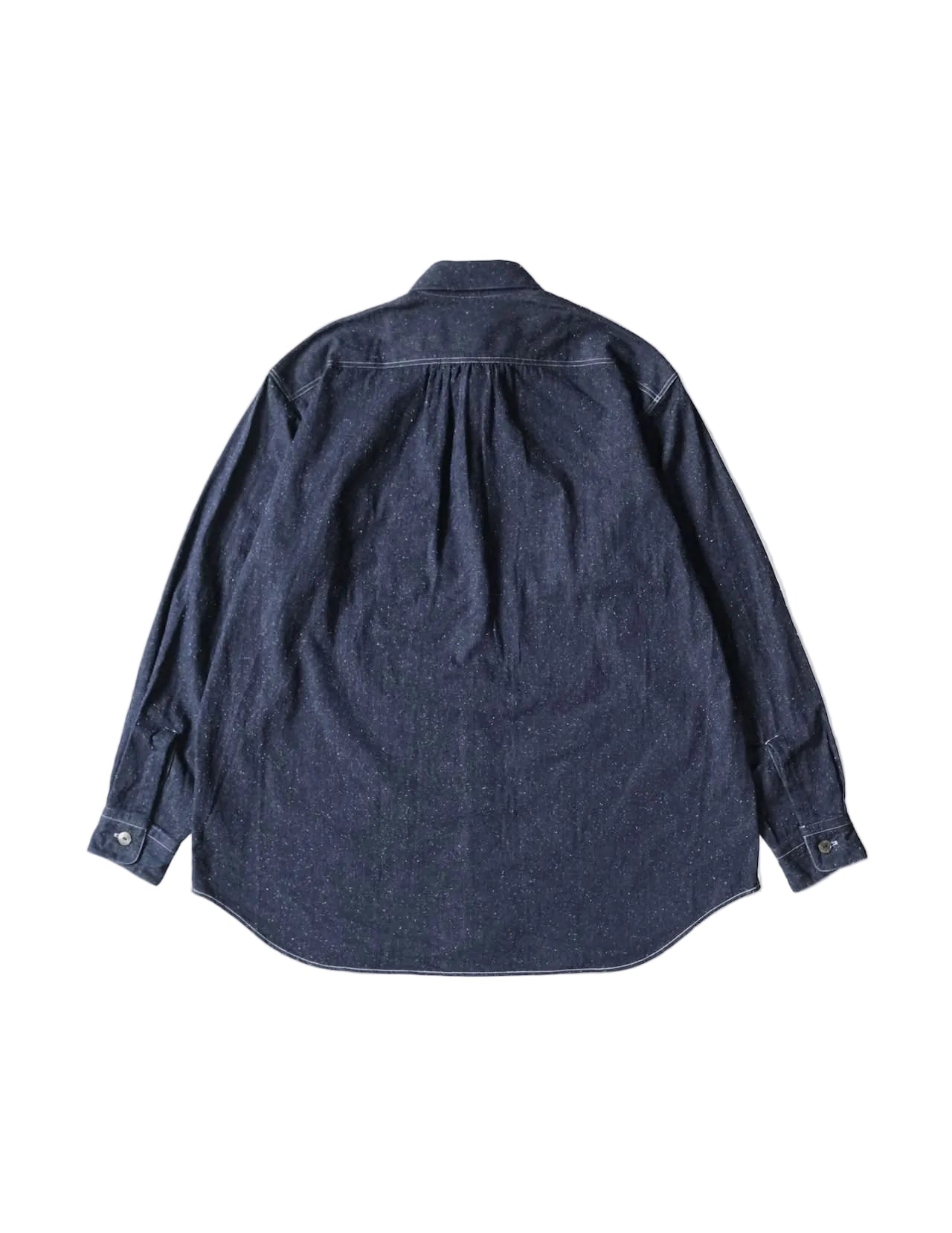 A dark indigo denim long-sleeve shirt shown from the back, featuring a subtle pleated detail at the upper back and buttoned cuffs, laid flat against a light cream background.
