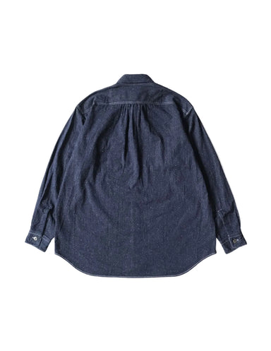 A dark indigo denim long-sleeve shirt shown from the back, featuring a subtle pleated detail at the upper back and buttoned cuffs, laid flat against a light cream background.