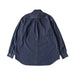 A dark indigo denim long-sleeve shirt shown from the back, featuring a subtle pleated detail at the upper back and buttoned cuffs, laid flat against a light cream background.
