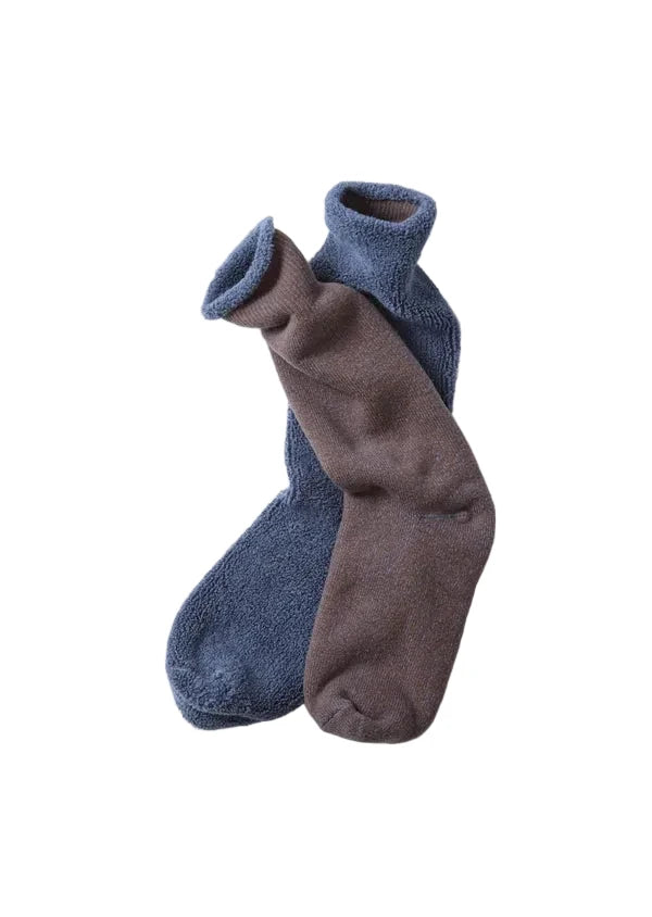 Two plush crew socks, one in dusty blue and one in taupe-brown, arranged overlapping on a clean white background.