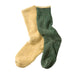 A pair of split-color socks, with one half in a soft mustard yellow and the other half in a heathered dark green, laid flat on a light gray background.