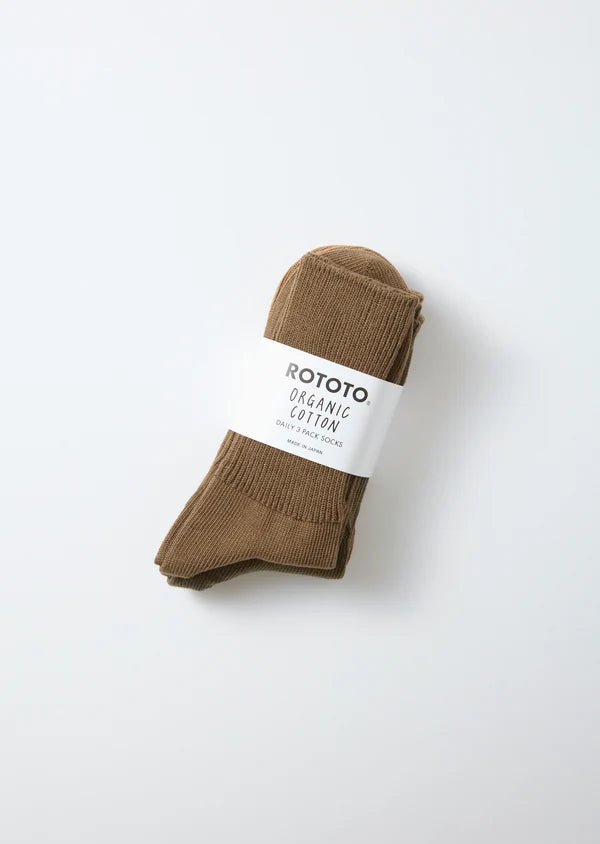 A pair of brown cotton crew socks rolled up with a white paper band labeled 'ROTOTO ORGANIC COTTON', photographed on a clean white background.