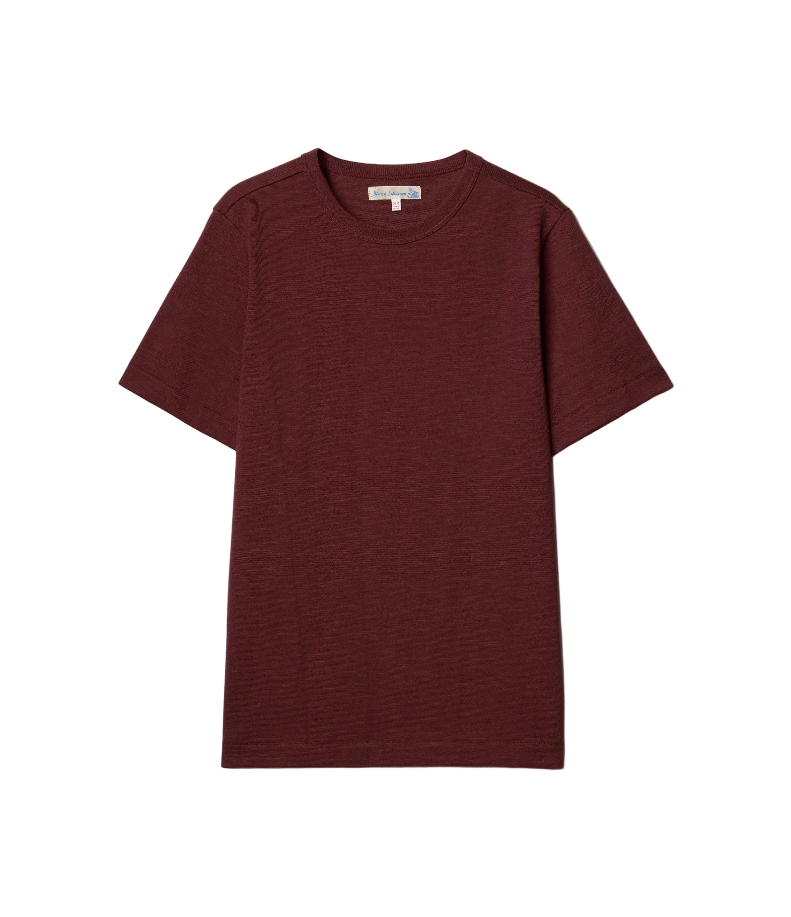 A short-sleeve crewneck t-shirt in a deep burgundy color, laid flat against a light off-white background.
