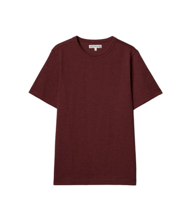 A short-sleeve crewneck t-shirt in a deep burgundy color, laid flat against a light off-white background.
