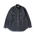 A dark gray indigo chambray button-down shirt with two chest pockets, laid flat against a light cream background.