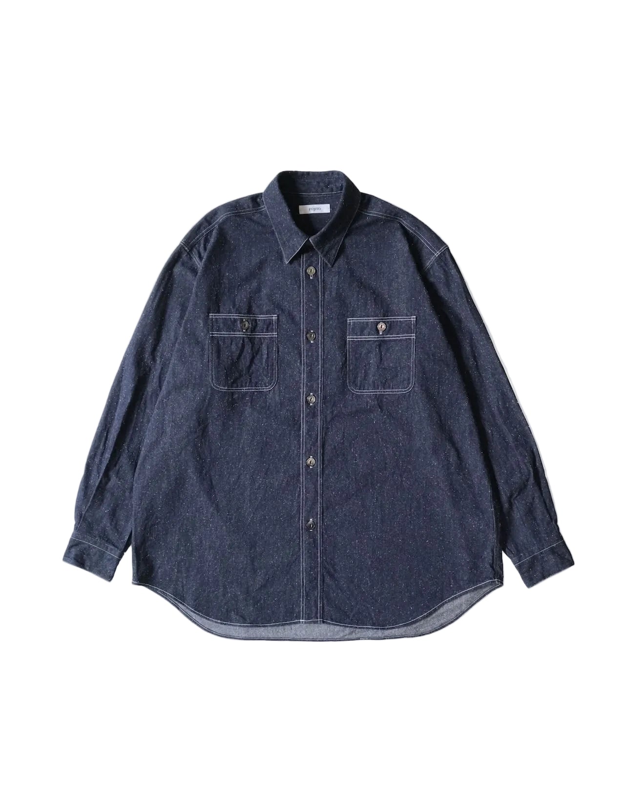 A dark indigo denim long-sleeve button-up shirt with two chest pockets, laid flat against a light cream background.