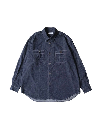A dark indigo denim long-sleeve button-up shirt with two chest pockets, laid flat against a light cream background.