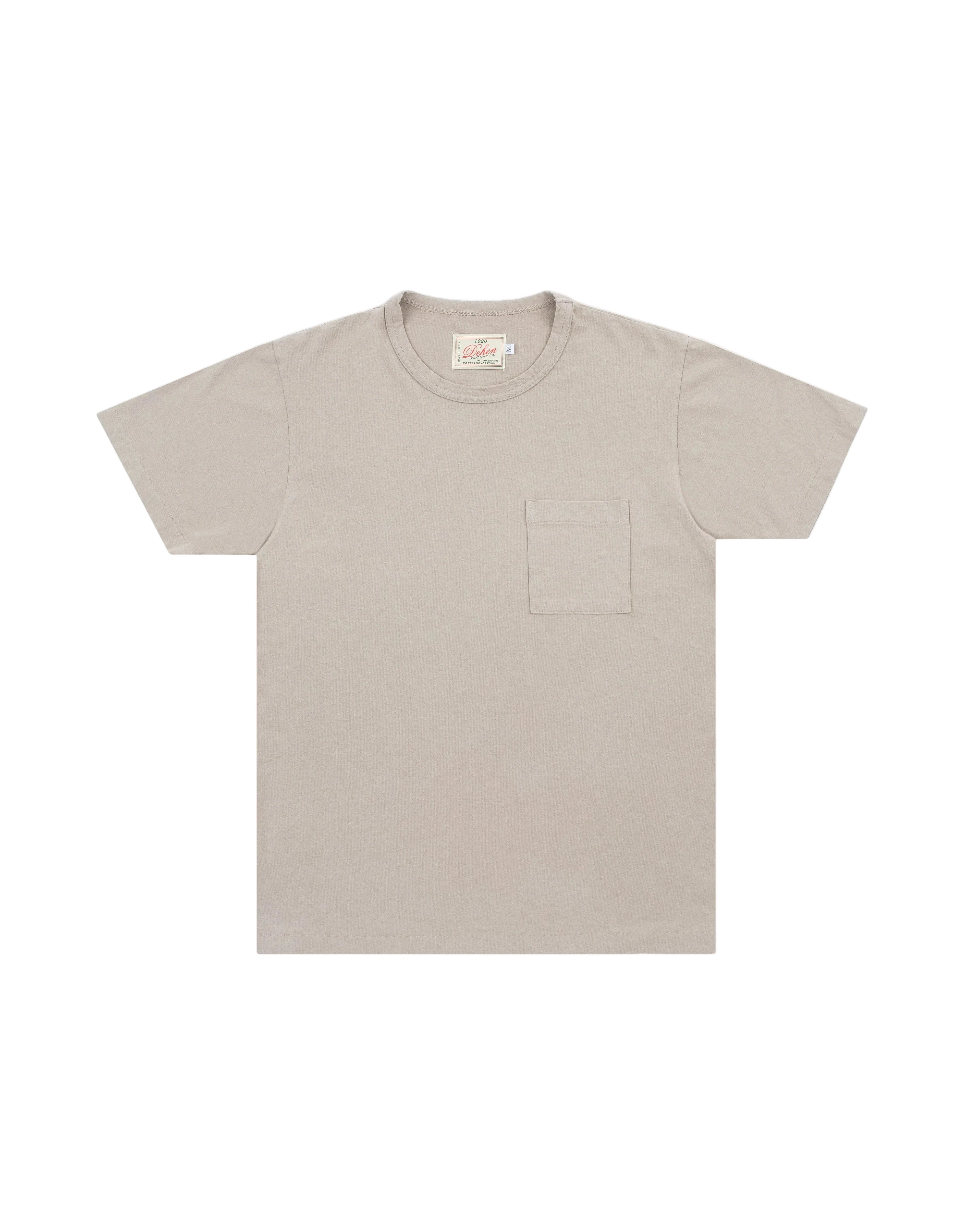 A light beige crewneck t-shirt with a single chest pocket, displayed flat against a light gray background.