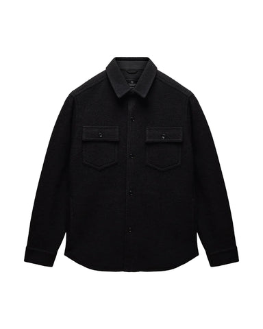 A black long-sleeve button-up shirt jacket with two buttoned chest flap pockets, displayed flat against a light gray background.