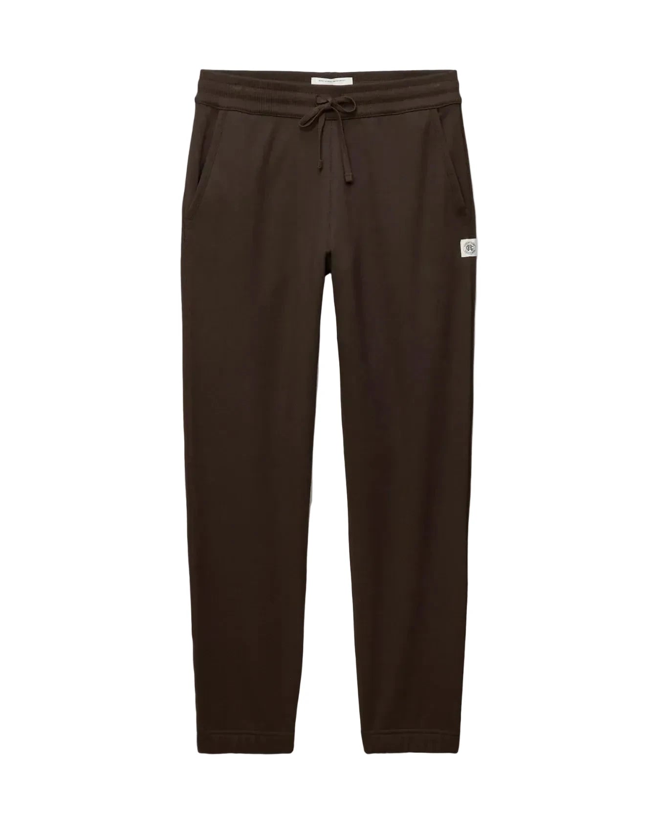 Dark brown jogger pants with an elastic drawstring waist and a small white brand tag on the left hip, shown flat against a light gray background.