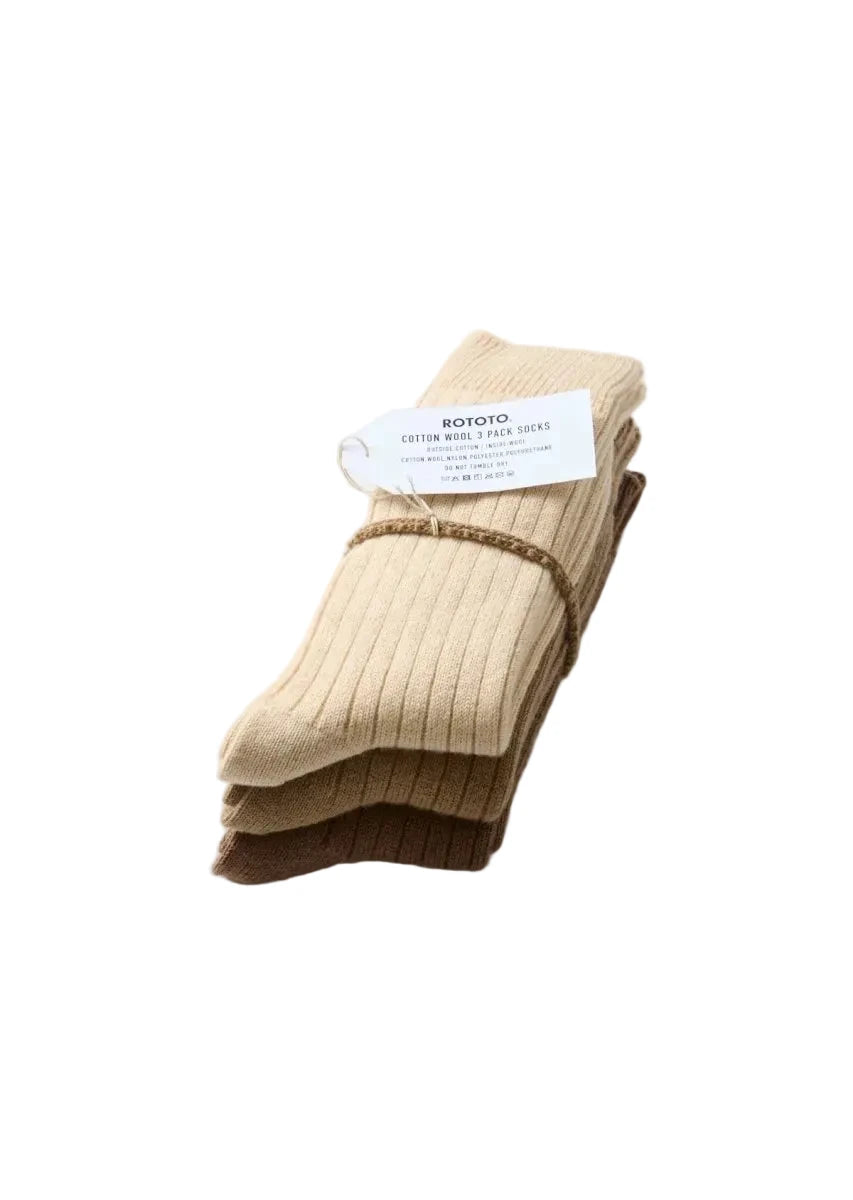 A stack of three ribbed cotton crew socks in beige, brown, and dark brown, tied with a brown elastic band and a white paper tag reading 'BOTOTO'.